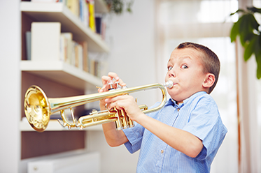 Kid playing on trumpet and looking at the camera with a funny face